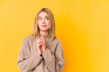 Sarışın genç kadın sarı arka planda izole edildi. Aklında bir plan oluşturdu, bir fikir oluşturdu..