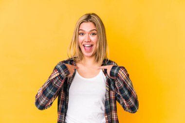 Sarışın, beyaz tenli, izole bir kadın. Parmakla işaret ederek şaşırmış, gülümseyerek..
