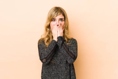 Sarışın, beyaz, düşünceli bir kadın. Ağzını eliyle kapatan bir fotokopi odasına bakıyor..