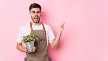 Kafkasyalı genç bahçıvan elinde bir bitki tutuyor.