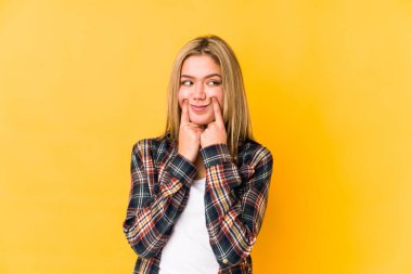 Sarışın, beyaz bir kadın, sarı arka planda izole edilmiş ve iki seçenek arasında kalmış..