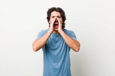 Beyaz arka planda genç yakışıklı bir adam heyecanlı bir şekilde bağırıyor..