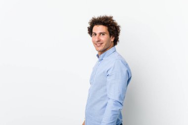 Zarif bir gömlek giyen genç, kıvırcık, olgun bir adam gülümseyen, neşeli ve keyifli bir kenara bakar..