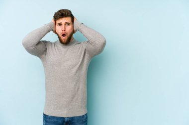 Mavi arka planda izole genç beyaz adam şok oldu, o önemli bir toplantı hatırladı.