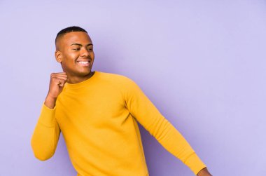 Mor arka planda izole edilmiş genç Latin adam dans ediyor ve eğleniyor..