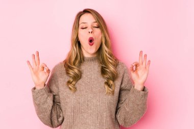 Pembe arka planda izole edilmiş genç beyaz kadın sıkı çalışma gününden sonra dinleniyor, yoga yapıyor..