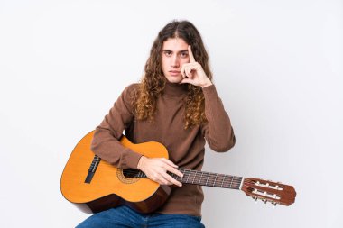 Gitar çalan Kafkasyalı genç bir adam kendini izole edip parmağıyla şakağı işaret ediyor, düşünüyor ve bir göreve odaklanıyor..