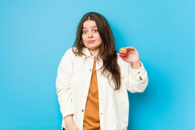 Kurabiye tutan genç kadın omuzlarını silker ve gözleri açık kalır..