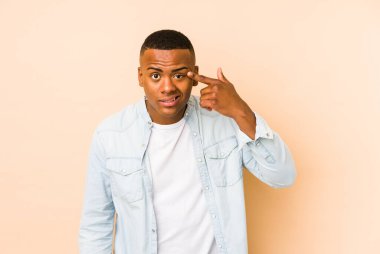 Bej arka planda izole edilmiş genç latin adam işaret parmağıyla bir hayal kırıklığı gösteriyor..