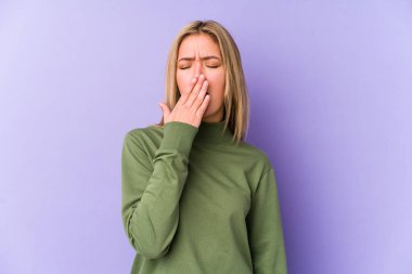 Sarışın, beyaz bir kadın kendini izole etmiş esniyor. Ağzı eliyle kapatan yorgun bir hareket sergiliyor..