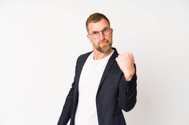 Beyaz arka planda izole edilmiş kıdemli iş adamı kameraya yumruk gösteriyor, agresif yüz ifadesi var..