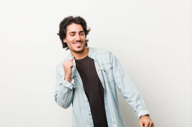 Beyaz bir arka plana karşı genç yakışıklı adam dans ediyor ve eğleniyor..