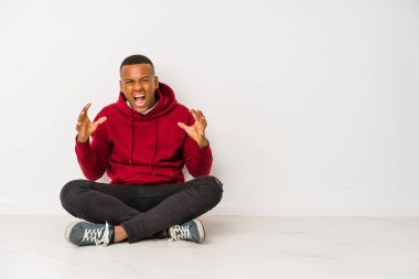 Genç Latin bir adam yerde oturmuş öfkeyle bağırıyordu..