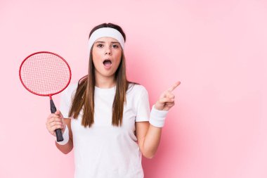 Badminton oynayan beyaz bir kadın, bir kenarı işaret ederek izole edilmiş.