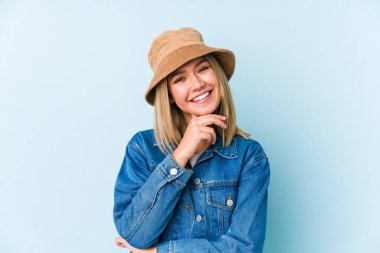 Sarışın, beyaz tenli bir kadın izole edilmiş mutlu ve kendinden emin gülümsüyor, elleriyle çenesine dokunuyor..