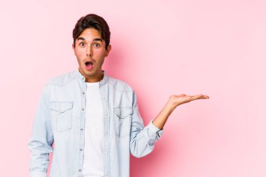 Pembe arka planda poz veren beyaz bir genç. Palmiye üzerinde kopya alanı tutmaktan etkilenmiş..