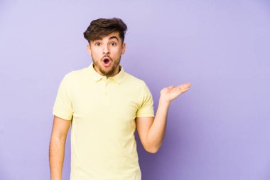 Mor arka planda izole edilmiş genç bir Arap, avuç içi fotokopi alanını tutmaktan etkilenmiş..