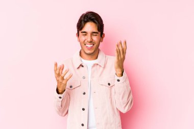 Pembe arka planda poz veren beyaz bir genç neşeli bir şekilde gülüyor. Mutluluk kavramı.