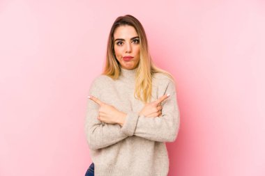 Orta yaşlı bir kadın, izole edilmiş arka planda iki seçenek arasında seçim yapmaya çalışıyor..