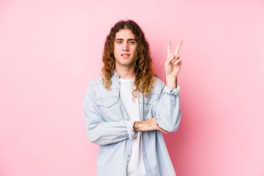 Uzun saçlı adam yalnız poz veriyor. İki numarayı parmaklarıyla gösteriyor..