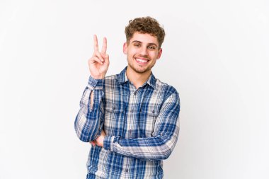 Sarışın, kıvırcık saçlı, beyaz tenli bir adam iki numarayı parmaklarıyla gösteriyor..