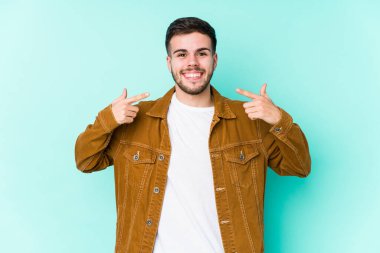 Genç yakışıklı adam gülümsüyor, parmaklarıyla ağzını işaret ediyor..