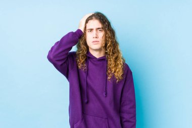 Uzun saçlı adam yalnız poz veriyor. Çok yorgun ve uykulu. Elini başının üstünde tutuyor..