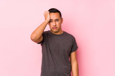 Pembe arka planda poz veren seni gidi Latin adam. Yorgun ve uykulu. Elini başının üstünde tutuyor..