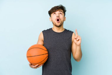 Genç Arap bir adam açık ağızla üst tarafı işaret ederek basket oynuyor..