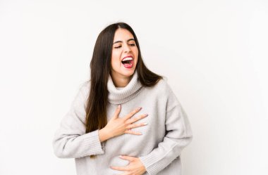 Beyaz arka planda soyutlanmış beyaz bir kadın mutlu bir şekilde gülüyor ve ellerini karnının üstünde tutarak eğleniyor..