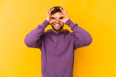 Sarı arka planda izole edilmiş genç beyaz adam gözlerinde sorun olmadığını gösteriyor.