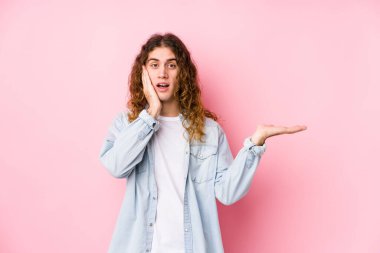 Uzun saçlı adam yalnız poz veriyor, avuç içinde fotokopi alanı tutuyor, el üstünde tutuyor. Şaşırmış ve mutlu..