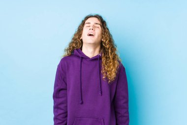 Uzun saçlı adam yalnız poz veriyor rahat ve mutlu gülüyor, boynunu uzatmış dişlerini gösteriyor..