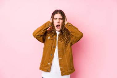 Uzun saçlı genç adam, yalıtılmış poz veriyor. Kulakları elleriyle kapatıyor. Gürültülü sesler duymamaya çalışıyor..