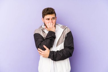 Mor arka planda izole edilmiş, tırnak yiyen, gergin ve endişeli genç bir adam..