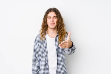 Genç, uzun saçlı adam kameraya el sallayarak selam veriyor..