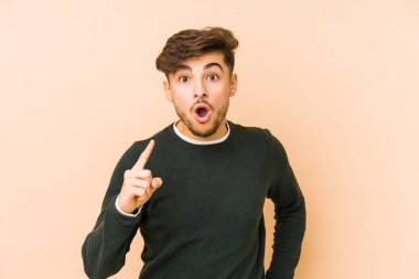 Genç Arap bir adam bej bir arka planda izole edilmiş. Bir fikri, ilham verici bir fikri var..