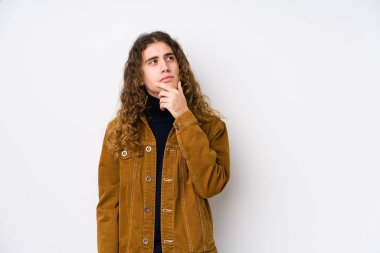 Uzun saçlı adam şüpheli ve şüpheci ifadesiyle yanlamasına poz veriyor..