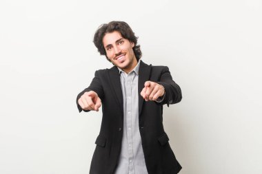 Genç iş adamı beyaz bir arka plana karşı Neşeli gülümsemeler ön tarafı işaret ediyor.