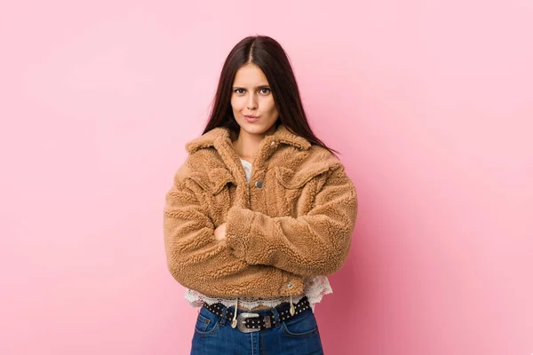 Young cute woman frowning face in displeasure, keeps arms folded.