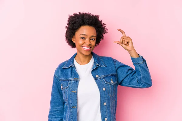 一个年轻的非洲裔美国女人面对着一个粉红的背脊孤立地拿着一个小指头 微笑着 自信着 — 图库照片