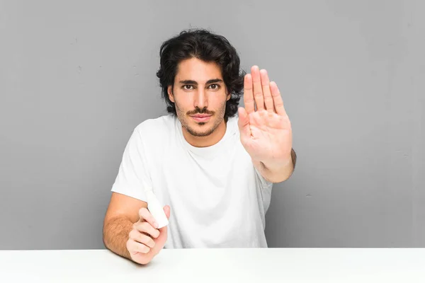 Jongeman Houdt Een Neusspray Staande Met Uitgestrekte Hand Met Stopteken — Stockfoto