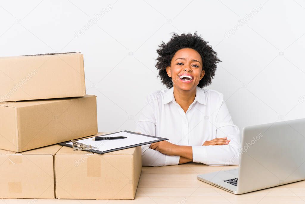 Warehouse manager sitting checking deliveries with laptop laughing and having fun.