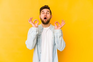 Sarı arka planda izole edilmiş genç beyaz adam sıkı çalışma gününden sonra rahatlıyor. Yoga yapıyor..