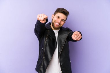 Mor arka planda soyutlanmış genç bir adam. Neşeli gülücükler öne bakıyor..