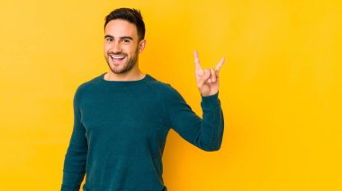 Sarı fırında izole edilmiş genç beyaz adam boynuzlarını devrim konsepti olarak gösteriyor..