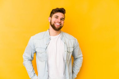 Sarı arka planda izole edilmiş genç beyaz adam mutlu, güler yüzlü ve neşeli..