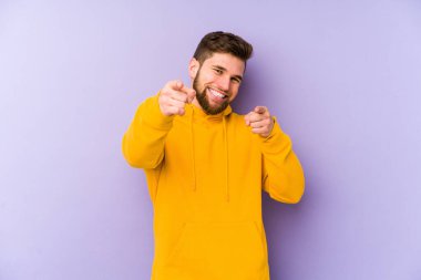 Mor arka planda soyutlanmış genç bir adam. Neşeli gülücükler öne bakıyor..