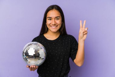 Genç Asyalı bir kadın top partisi veriyor. İki numarayı parmaklarıyla gösteriyor..