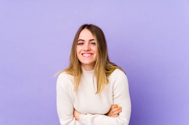 Mor arka planda izole edilmiş genç beyaz kadın gülüyor ve eğleniyor..
